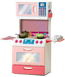 Pink and cream Barbie play kitchen with a microwave above the cooktop, an oven below and pretend food on the counter.